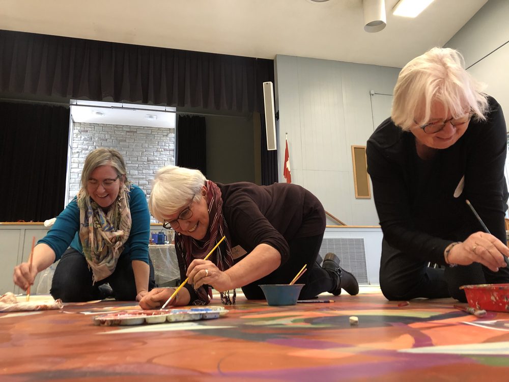 Participants painting a panel together
