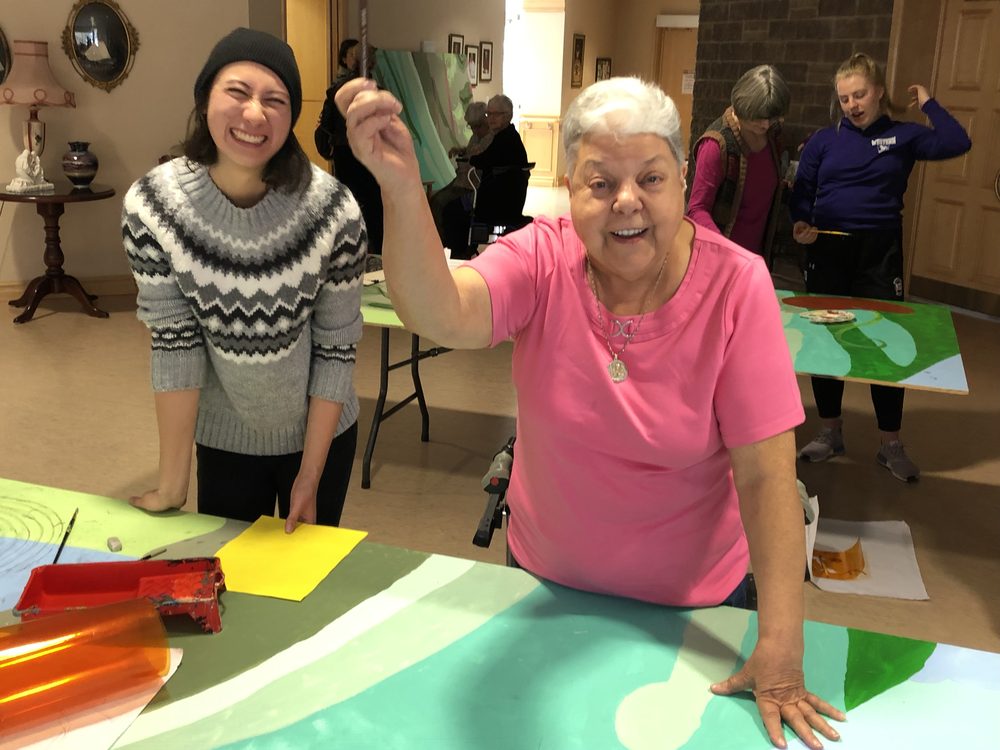 Participants smiling beside the panels they painted