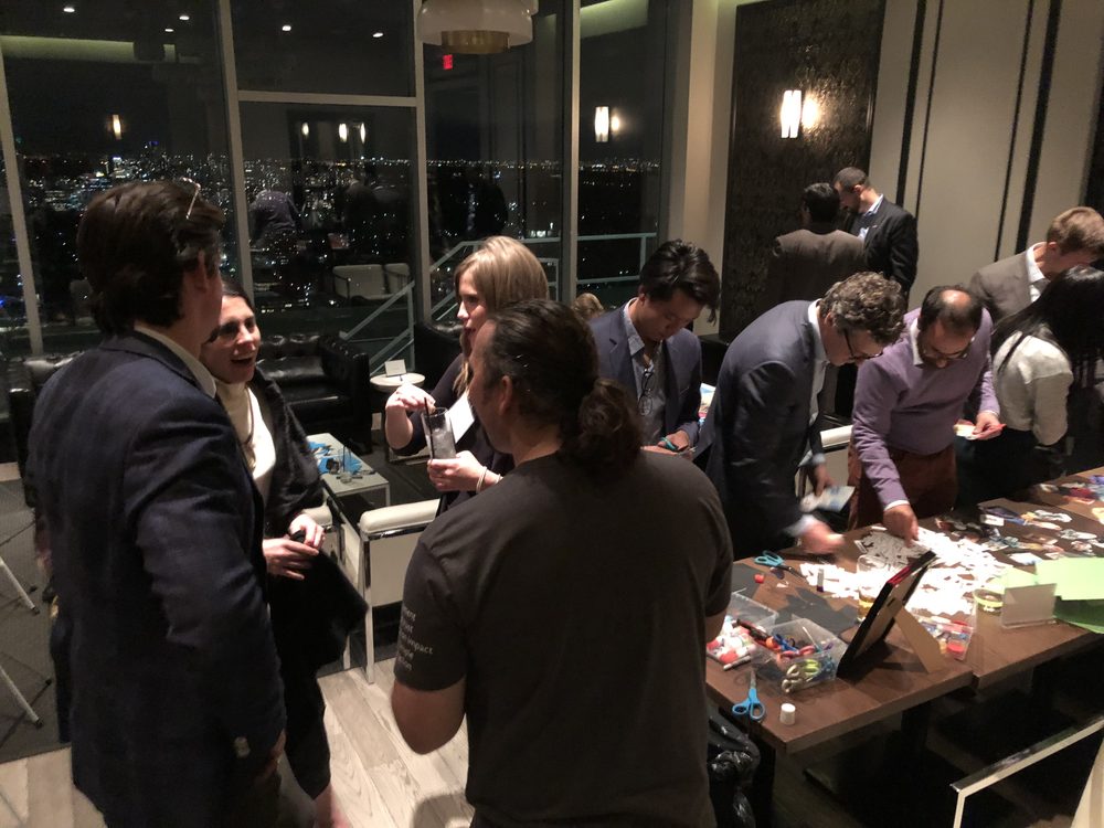 Guests at an evening corporate event gathered around a collage table