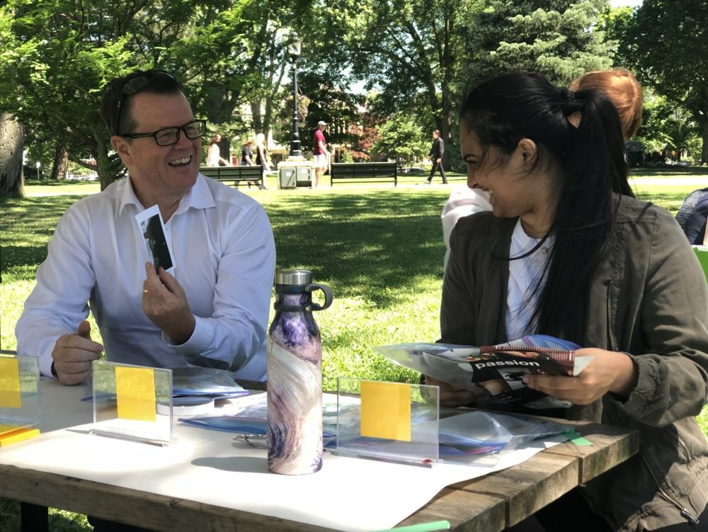 A city official and a young person talking over art materials at a picnic table