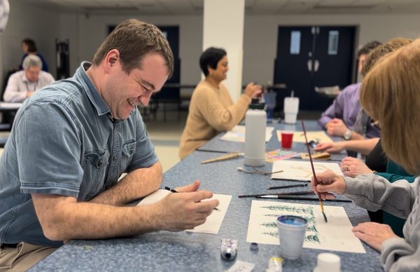 Students and staff drawing at tables